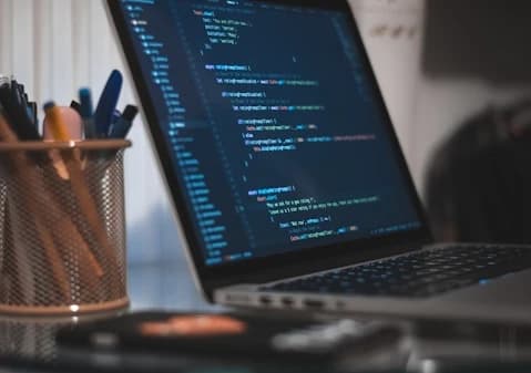 コードエディタを表示したノートパソコンのある作業デスク